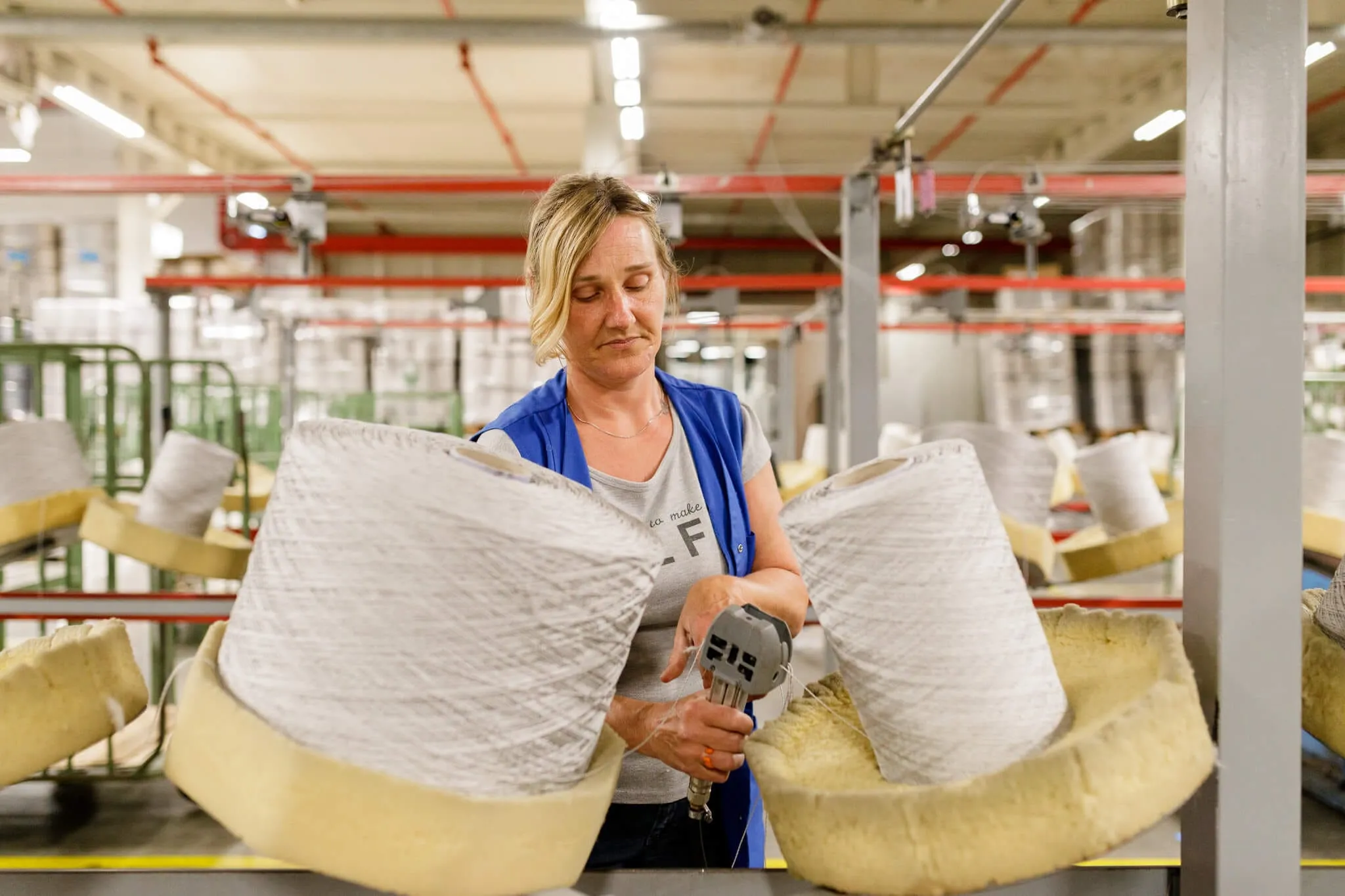 Medewerker in de spinnerij met twee spoelen garen