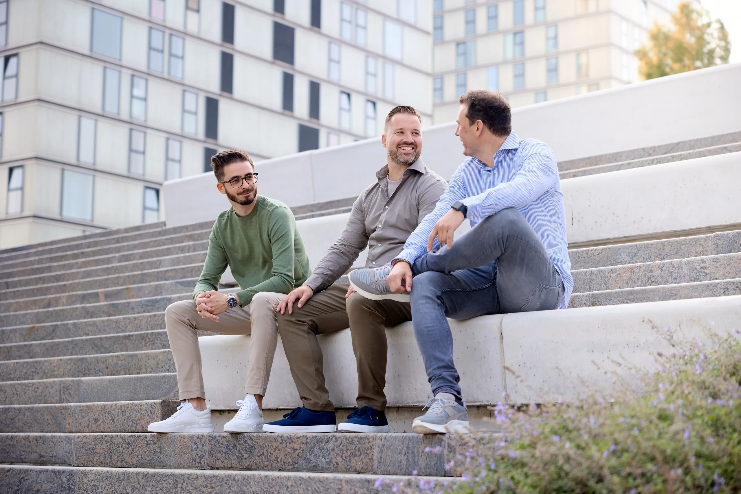 Drie medewerkers zitten lachend op een trap